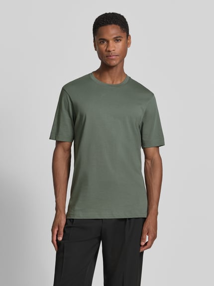 Männermodel trägt Slim Fit Poloshirt mit V-Ausschnitt Modell 'Braian' von Drykorn aus Reine Baumwolle mit Strukturmuster, Ganzkörperansicht von vorne.