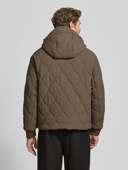 Männermodel trägt Jacke mit Steppnähten und Label-Detail von Armani Exchange in Braun, Struktur durch Steppnähte, Ganzkörperansicht Rückansicht. Rückenlänge 69 cm, Schulterbreite 46 cm, Brustweite 59 cm, Ärmellänge 67 cm, Regular Fit, Kapuze mit Tunnelzug, Zweiwege-Reißverschluss, Eingrifftaschen mit Knopfverschluss.