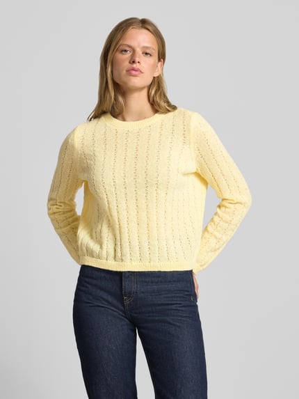Frauenmodel trägt Regular Fit Pullover mit gerippten Ärmelbündchen Modell 'ADA' von PIECES in Hellgelb mit feiner Strickstruktur, Nahaufnahme Oberkörper. Damen Pullover von PIECES.