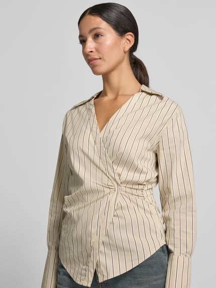 Frauenmodel trägt Slim Fit Bluse in Wickel-Optik von COMMA, beige mit dunkelblauen Streifen, Baumwoll-Mix, Nahaufnahme Oberkörper.