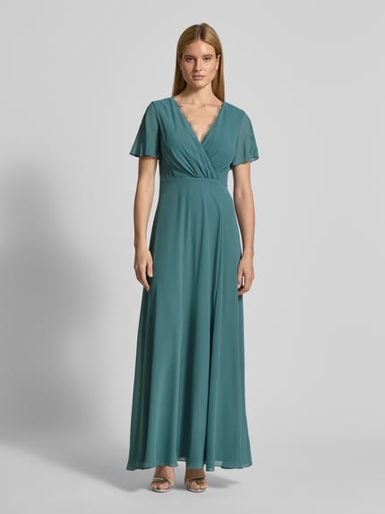 Frauenmodel trägt Damen Abendkleid mit Spitzenbesatz von Christian Berg Cocktail in Taillierter Passform, V-Ausschnitt, Wickel-Optik, semitransparentem, kurzärmeligem Design, in Petrol, fließender Stoff, Ganzkörperansicht von vorne.