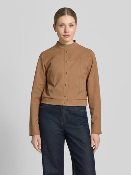 Kobiece modelka nosi Jacke mit Stehkragen und Knopfleiste von monari w kolorze karmelowym, szwy działowe, krój regular fit, długość tyłu w rozmiarze 36: 46 cm, szerokość ramion w rozmiarze 36: 36 cm, szerokość klatki piersiowej w rozmiarze 36: 48 cm, długość rękawów w rozmiarze 36: 63 cm, widok całej sylwetki z przodu.