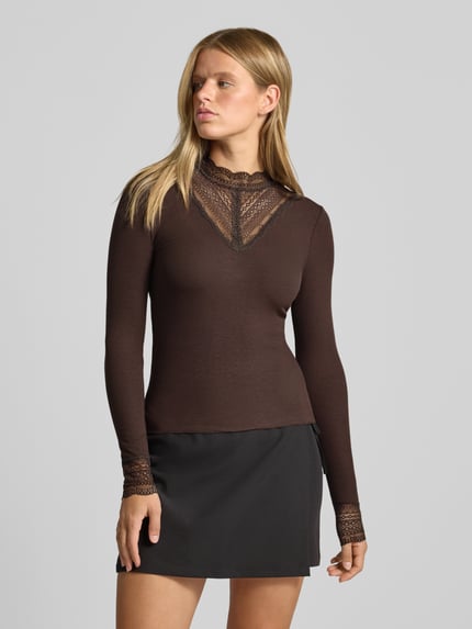 Frauenmodel trägt Slim Fit Langarmshirt aus Viskose-Mix Modell 'TILDE' von ONLY in Dunkelbraun mit Spitze, Damen Langarmshirt von ONLY, Nahaufnahme Oberkörper.