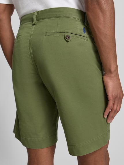 Męski model nosi Straight Fit Chinoshorts aus Baumwoll-Mix od Polo Ralph Lauren, efekt: jednolity kolor, detal z logo, szlufki na pasek, zapięcie na guzik i ukryty zamek błyskawiczny, tylne kieszenie, wpuszczane kieszenie boczne, mieszanka bawełny, całkowity widok z tyłu.