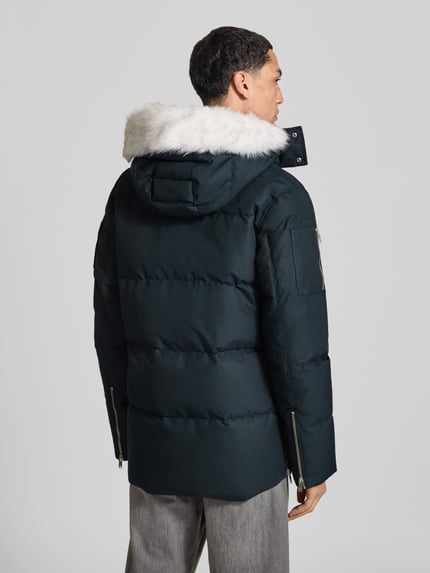 Männermodel trägt Daunenjacke mit abnehmbarer Fellkapuze von Moose Knuckles, unifarben, strukturierte Webware, Longline, Rückansicht.