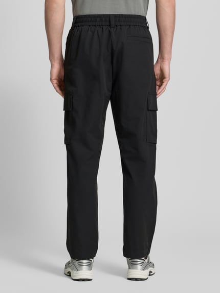 Männermodel trägt Relaxed Fit Cargohose mit Gürtelschlaufen Modell 'SRACKY' von BOSS Orange, Optik: Unifarben, Passform: Relaxed-Fit, Label-Patch, seitliche Eingrifftaschen, Gesäßtaschen, Cargotaschen, Ganzkörperansicht Rückansicht.