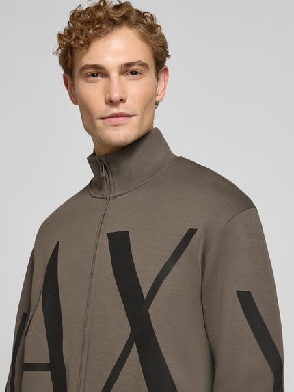 Męski model nosi bluza rozpinana z mieszanki bawełny od Armani Exchange, nadruk z logo, prążkowane wykończenia, zamek błyskawiczny dwustronny, luźny krój, długość tyłu w rozmiarze M: 67 cm, długość rękawów: 63 cm, ujęcie z przodu, zbliżenie na górną część ciała.