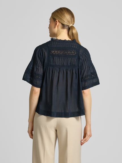 Frauenmodel trägt Blusenshirt mit V-Ausschnitt Modell 'Siama' von Neo Noir in Dunkelblau mit Stitchings, Regular-Fit, Rückenlänge 56 cm, Ärmellänge 28 cm, Ganzkörperansicht Rückansicht.