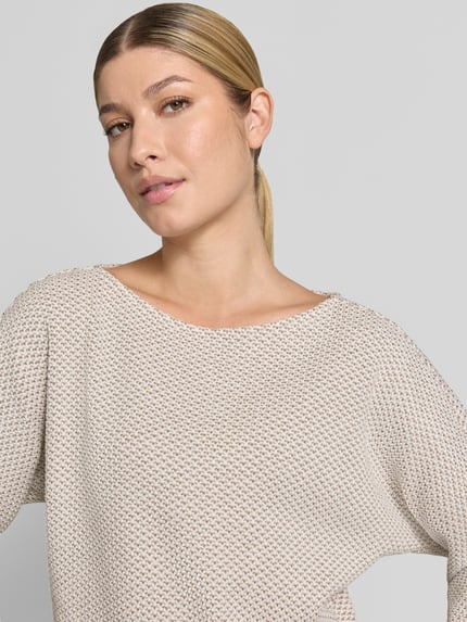 Frauenmodel trägt Loose Fit Pullover mit Baumwoll-Anteil Modell 'Sassoni' von OPUS, beige meliert, grob strukturierte Textur, Nahaufnahme Oberkörper. Damen Pullover von OPUS.