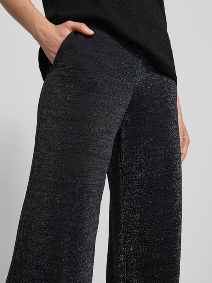 Vrouwenmodel draagt Stoffhose met elastischem Bund van Milano Italy, zwarte glitter-look, Franse steekzakken, detailopname heupen.