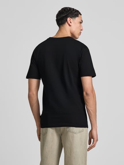 Männermodel trägt T-Shirt mit Label-Stitching Modell 'CASSICA' von Ellesse, Schwarz, Reine Baumwolle, Gerader-Schnitt, Rückenansicht, Ganzkörperansicht Rückansicht.