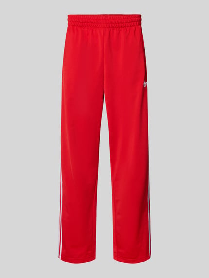 Produktfoto, Sweatpants mit elastischem Bund von adidas Originals in Rot mit weißem Label-Stitching, Reißverschlusstaschen, lockerer Schnitt.
