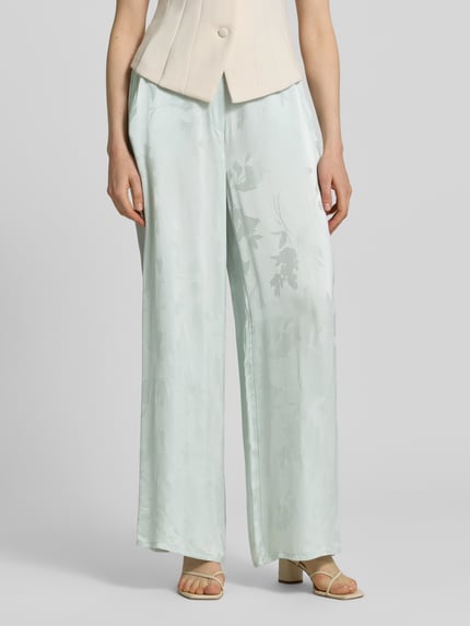 Frauenmodel trägt Weite Hose aus reiner Viskose von Calvin Klein Womenswear in Hellgrün mit Allover-Jacquardmuster, seitliche Taschen, Nahaufnahme Unterkörper.