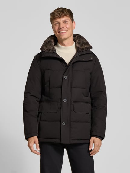 Männermodel trägt Steppjacke mit Kapuze Modell 'PIAZZA' von Strellson in Unifarbe, sichtbare Knöpfe, Pattentaschen, Ganzkörperansicht von vorne.