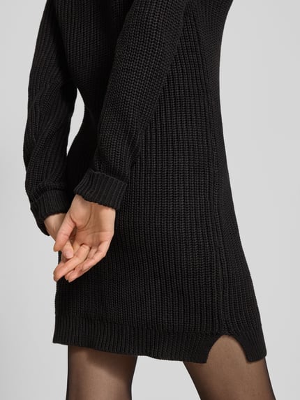 Frauenmodel trägt Strickkleid mit Rundhalsausschnitt Modell 'SIESTA' von Noisy May, Baumwoll-Mix, schwarze Struktur, gerader Schnitt, Ganzkörperansicht Rückansicht.