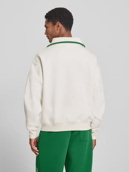 Männermodel trägt Loose Fit Troyer aus Baumwoll-Mix Model 'Tennisc' von Lacoste in Weiß und Grün, Ganzkörperansicht Rückansicht, Herren Troyer von Lacoste.