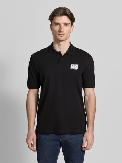 Männermodel trägt Regular Fit Poloshirt mit Knopfleiste von ARMANI EXCHANGE aus Baumwoll-Elasthan-Mix, Label-Print, elastische Ärmelbündchen, schwarze Farbe, Ganzkörperansicht von vorne. Rückenlänge bei Größe M: 70 cm.