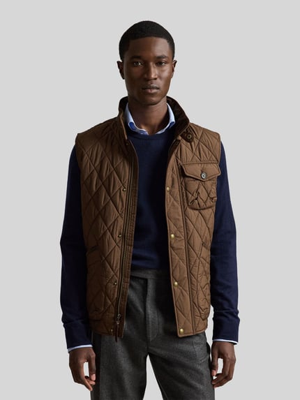 Męski model nosi brązową pikowaną kamizelkę Regular Fit Weste mit Logo-Patch model 'BEATON' od Polo Ralph Lauren, widok całej sylwetki z przodu.