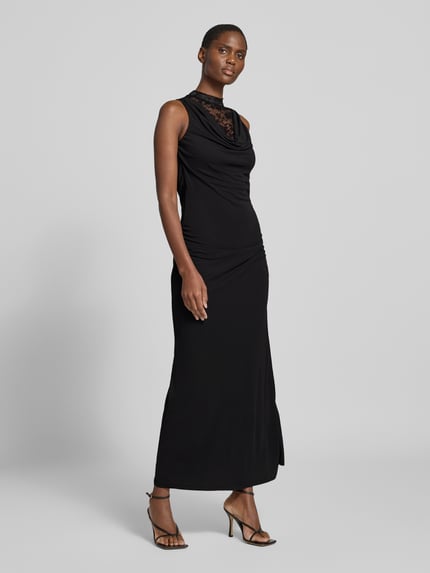 Frauenmodel trägt Maxikleid mit Spitzenrückenausschnitt von VERO MODA in Schwarz, ärmellos, Wasserfallausschnitt, reines Polyester, Ganzkörperansicht von vorne.