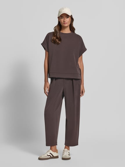 Frauenmodel trägt Sweatpants aus Modal-Mix mit Bundfalten von Rich & Royal in Dunkelbraun, weite Form, elastischer Bund, Ganzkörperansicht von vorne.