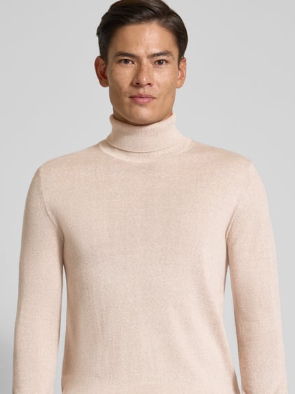Männermodel trägt Pullover aus Merino-Mix mit Rollkragen von Christian Berg Men in Beige, feine Struktur, körpernah, Nahaufnahme Oberkörper.