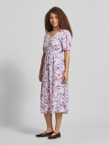 Modelka nosi tailliertes Freizeitkleid aus Viskose-Baumwoll-Mix von Marc O'Polo Denim, efekt: wzór na całej powierzchni, krój taliowany, długość midi, dekolt w serek, szlufki na pasek, krótka listwa guzikowa, taśma do wiązania, bufiaste rękawy, zakończenia rękawów elastyczne, wpuszczane kieszenie, mieszanka wiskozy i bawełny; widok całej sylwetki z przodu