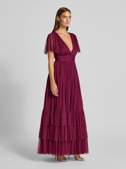 Kobieta modelka nosi sukienkę wieczorową z głębokim dekoltem w serek od LACE & BEADS, linia a, długa, efekt stopniowania, tasiemka w talii, długość tyłu w rozmiarze S: 149 cm, szerokość w rozmiarze S: 38 cm, długość rękawów w rozmiarze S: 27 cm, pełny widok od przodu