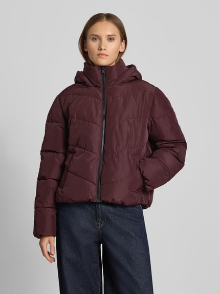 Frauenmodel trägt Regular Fit Steppjacke mit Kapuze Modell 'CLAIR' von ONLY in Dunkelrot, sichtbare Steppnähte, Damen Steppjacke, Ganzkörperansicht von vorne.