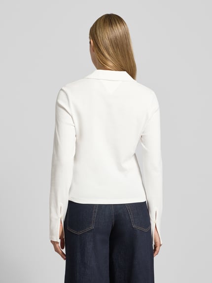 Frauenmodel trägt Slim Fit Langarmshirt aus reiner Baumwolle von Tommy Hilfiger, weiß, V-Ausschnitt, Logo-Detail, Rückansicht Ganzkörperansicht.