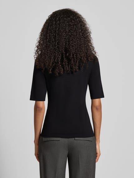 Vrouwenmodel draagt nauwsluitend dames T-shirt met stretch, model 'Serta' van Opus, mix van katoen en elastaan, halflange mouwen, U-hals, ruglengte maat 36: 58 cm, volledig van achteren gezien.