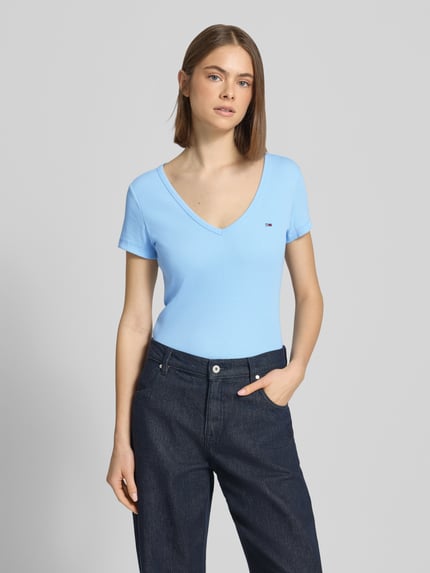 Vrouwenmodel draagt Slim Fit T-shirt uit katoenmix van Tommy Jeans in effen kleuren met gestikt logo, ronde hals en korte mouw, jersey materiaal, vooraanzicht bovenlichaam.