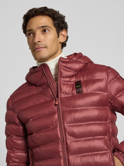 Männermodel trägt Steppjacke mit Zweiwege-Reißverschluss Modell 'CHARLES' von Blauer USA in Rot, glatte Textur, Nahaufnahme Oberkörper.