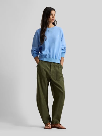 Frauenmodel trägt Comfort Fit Sweatshirt aus Baumwoll-Mix von Polo Ralph Lauren in Hellblau mit Logo-Stitching, unifarben, Ganzkörperansicht von vorne.