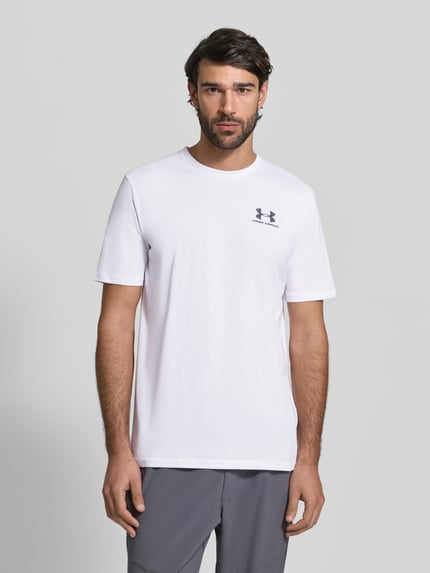 Männermodel trägt Regular Fit T-Shirt mit Logo-Print Modell 'Left' von Under Armour aus Baumwoll-Mix, weiß, Rundhalsausschnitt, Ganzkörperansicht von vorne. Herren T-Shirt Rückenlänge bei Größe M 72 cm.