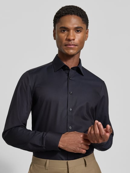 Männermodel trägt Body Fit Businesshemd aus Baumwoll-Mix von OLYMP in dunklem Blau, matter Stoff, Nahaufnahme Oberkörper, Herren Businesshemd von OLYMP Level 5.