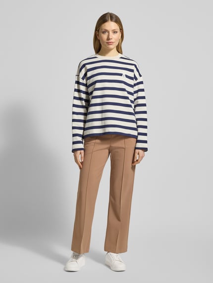 Frauenmodel trägt Stoffhose mit elastischem Bund Modell 'RENEE' von Raffaello Rossi in Beige, Material-Mix mit Stretch-Anteil, Gerader-Schnitt, Bundfalten, Französische-Eingrifftaschen, Gesäßtaschen, Ganzkörperansicht von vorne.