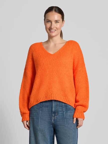 Frauenmodel trägt Oversized Strickpullover mit Mohair-Anteil von Oui in Orange mit gerippten Abschlüssen, Material-Mix, Ganzkörperansicht von vorne.