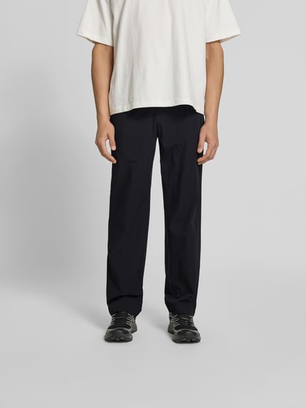 Männermodel trägt Stoffhose mit Stretch-Anteil von Forét in Schwarz, Relaxed-Fit, Elastischer-Material-Mix, Ganzkörperansicht von vorne.