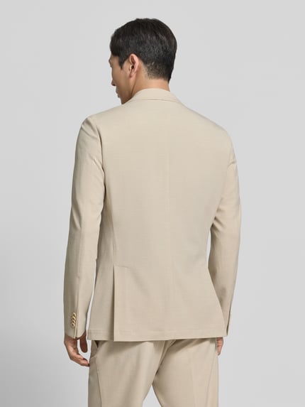 Männermodel trägt Sakko mit seitlichen Eingrifftaschen Modell 'Carter' von CG - Club of Gents, Beige, Material-Mix mit Viskose-Anteil, Rückenansicht, Regular-Fit, Knopfleiste, Brustleistentasche, Rückenlänge bei Größe 50: 75 cm, Schulterbreite: 41 cm, Ärmellänge: 67 cm. Ganzkörperansicht Rückansicht