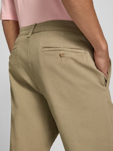 Mannelijk model draagt Straight Fit broek uit katoenmix van REVIEW, beige, steekzakken, achterzakken, knoop- en ritssluiting, detailopname achterkant. Context: heren broek van REVIEW, elastische katoenmix, straight fit, steekzakken, achterzakken, knoop- en ritssluiting, bandwijdte bij maat M: 42 cm, binnenbeenlengte bij maat M: 69 cm.