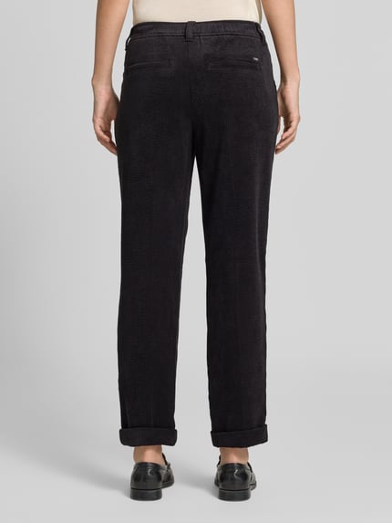 Frauenmodel trägt Cordhose mit elastischem Bund von Christian Berg Woman in dunklem Material-Mix mit Stretch-Anteil, strukturierte Oberfläche, Tapered Fit, angedeutete Gesäßleistentaschen, seitliche Eingrifftaschen, Bundweite bei Größe 36: 38 cm, Innenbeinlänge 70 cm, Ganzkörperansicht Rückansicht.