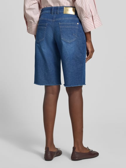 Vrouwenmodel draagt korte jeans Jeansshorts mit Fransen Modell 'Rich' van MAC in blauw, mix van katoen en elastaan, relaxed fit, steekzakken, franjesdetail bij zoom, bandwijdte maat 36: 41 cm, binnenbeenlengte maat 36: 33 cm. Ganzkörperansicht Rückansicht.