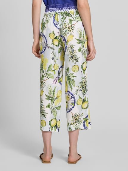 Frauenmodel trägt Straight Fit Stoffhose aus reiner Viskose mit Allover-Motiv-Print von Marc Cain, Damen Stoffhose, Teilelastischer Bund, verkürzte Passform, Bundweite bei Größe 36: 40 cm, Innenbeinlänge 64 cm, Ganzkörperansicht Rückansicht.
