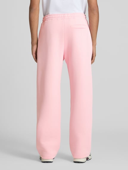 Männermodel trägt Straight Fit Sweatpants Baumwoll-Mix von REVIEW in Hellrosa mit Gesäßtasche und elastischem Bund, Ganzkörperansicht Rückansicht.