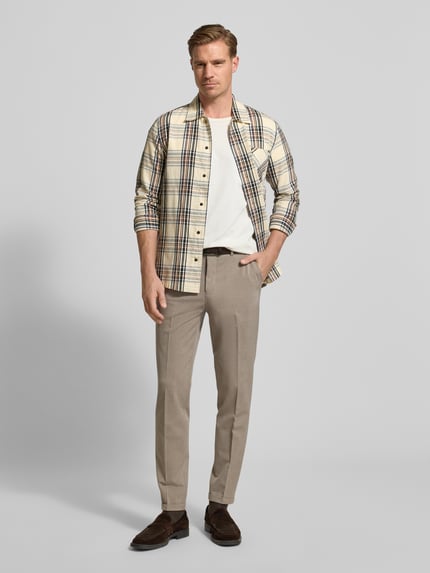 Männermodel trägt Stoffhose mit Bundfalten Modell 'liam' von Matinique, Material-Mix in Beige, gerader Schnitt, Ganzkörperansicht von vorne.