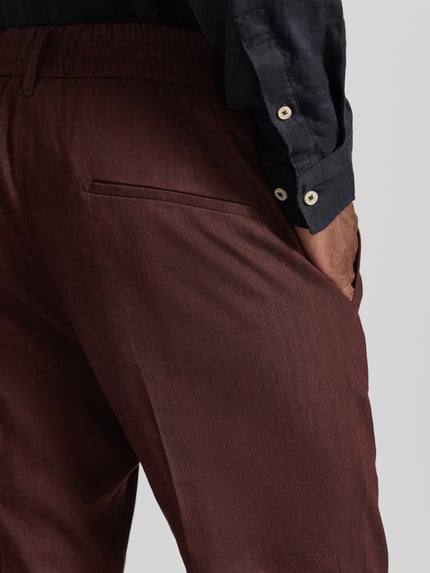 Männermodel trägt Hose aus Leinen-Mix mit Gesäßtaschen von Drykorn, Slim-Fit, Elastischer Bund, Nahaufnahme Gesäßtasche, Leinen-Viskose-Anteil.