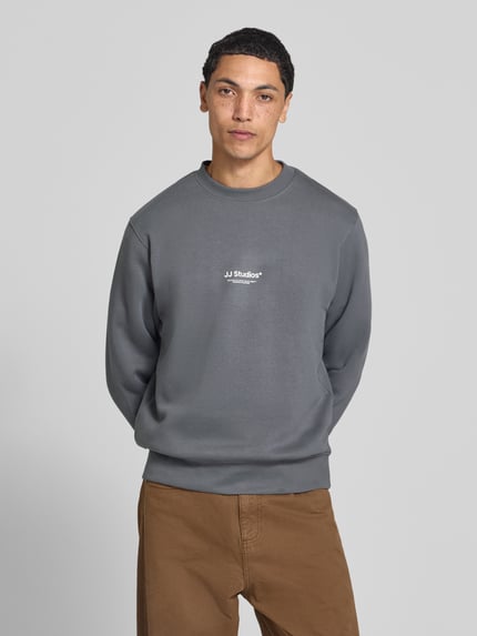 Männermodel trägt Regular Fit Sweatshirt aus Baumwoll-Mix Modell 'Soho' von JACK & JONES in Grau mit Logo-Print, Nahaufnahme Oberkörper. Baumwoll-Mix, elastische Abschlüsse, Rundhalsausschnitt, Rückenlänge 65 cm, Ärmellänge 66 cm.
