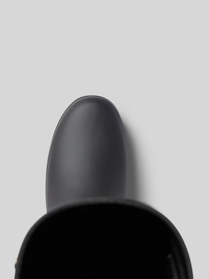 Produktfoto, Stiefel mit Label-Detail und Blockabsatz von Hunter, abgerundete Form in Grau, strukturierte Sohle, Detailaufnahme der Schuhspitze.