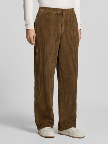 Männermodel trägt Regular Fit Hose mit seitlichen Eingrifftaschen von Lacoste in Cord, unifarben, strukturierte Oberfläche, Nahaufnahme Unterkörper.