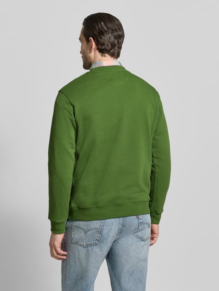 Mannenmodel draagt groen sweatshirt met ronde hals van Scotch & Soda, puur katoen, regular fit, labelstitching, ruglengte maat M 67 cm, mouwlengte 64 cm. Ganzkörperansicht Rückansicht.